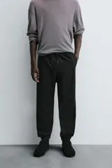 Pantalón tipo jogger de corte slim fit, confeccionado en tejido de algodón con elasticidad. Presenta cintura elástica ajustable con cordón, bolsillos frontales, bolsillos traseros de vivo y bajos con puños elásticos.