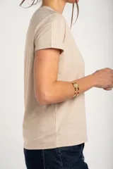 Remera de algodón peinado color marfil, de manga corta y corte al cuerpo, con escote en V ribeteado con hilo dorado.