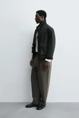 Pantalón de corte relajado en color verde militar, con diseño de pliegues frontales, bolsillos laterales y cierre de cremallera con botón.