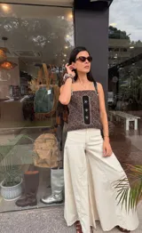 Top de tirantes con diseño artesanal, confeccionado en una combinación de tela estampada con motivos geométricos y un panel central negro con bordados de estrellas en color blanco. Presenta un corte recto y estilo casual.