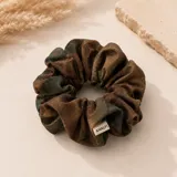Colero de tela con diseño fruncido y estampado camuflado en tonos tierra. Cuenta con una pequeña etiqueta de marca cosida en el borde.
