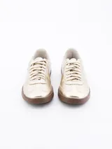 Zapatillas deportivas doradas con suela marrón y cordones al tono.