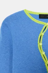 Chaqueta de punto color azul, con cuello redondo y manga larga. Presenta acabados en contraste de color verde neón y cierre frontal cruzado con botones.