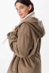 Campera de paño con capucha, cierre frontal con botones a presión y cordones ajustables en la cintura. Presenta un diseño de corte recto con mangas largas y puños ajustables.