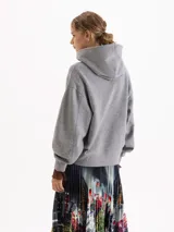 Buzo con capucha de calce amplio, color gris melange, con estampa frontal de un conejo sobre un auto amarillo. Posee mangas largas con puños acanalados.