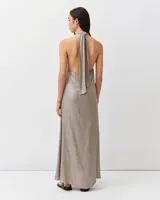 Vestido largo color dorado metalizado, con escote halter cruzado y silueta fluida de corte amplio.