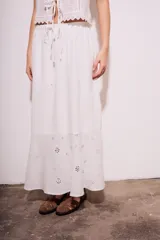 Falda larga blanca de viscosa y lino, con cintura elastizada y cordón ajustable. Presenta bordado calado con motivos florales en el ruedo.