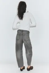 Jeans de tiro medio con diseño cropped, confeccionados en denim gris con efecto lavado. Presentan costuras laterales torcidas, trabillas para cinturón, cinco bolsillos y cierre frontal con cremallera y botón metálico.