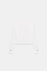 Camisa corta de cuello solapa y manga larga, con trabillas decorativas en los hombros. Presenta pliegues delanteros, elástico en la espalda y cierre frontal con botones.