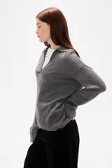 Sweater de punto color azul, con cuello polo y escote en V, de manga larga y diseño holgado.