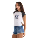 Remera Volcom de manga corta tipo raglán, modelo Kick It Game Day Crop Tee. Color blanco en el cuerpo con mangas y cuello en negro. Presenta un estampado frontal centrado con un diseño gráfico en tonos azules y negros.