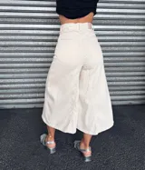 Pantalón capri color crudo, de tiro alto, pierna ancha y largo midi.