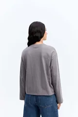 Remera de manga larga color beige, con cuello redondo y estampa gráfica frontal en color celeste.