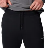 Pantalón tipo jogger de color negro, confeccionado en una mezcla de algodón, con cintura elástica ajustable mediante cordón interior, bolsillos laterales y traseros, y puños elásticos en los tobillos.