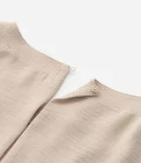 Blusa de manga corta color beige, confeccionada en tela texturizada. Presenta cuello redondo con detalle de pespuntes y cierre trasero con botón en forma de lágrima.