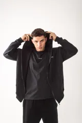 Campera con cierre frontal metálico, confeccionada en algodón pesado de alto gramaje. Presenta un diseño oversize con capucha, bolsillos tipo canguro y bordados minimalistas en el frente y en la manga.