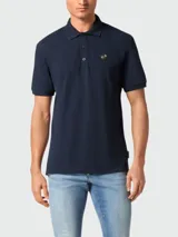 Polo de piqué azul marino con cuello clásico, tapeta de botones y logo metálico en el pecho.