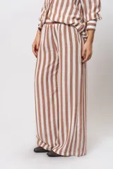 Pantalón largo de lino a rayas verticales color marrón y blanco, con cintura elástica y bolsillos laterales.