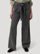 Pantalón de jean tiro alto con corte recto y pernera ancha. Presenta una pretina con lazo ajustable del mismo tejido, pinzas frontales y elástico en la parte posterior de la cintura.