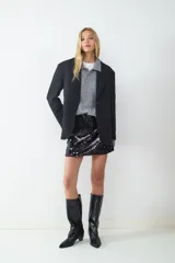 Blazer negro de corte recto y diseño oversize, con cuello de solapa, cierre frontal de dos botones y bolsillos con solapa en los laterales. Interior forrado.