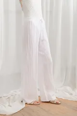 Pantalon de lino de corte ancho y tiro alto, con cintura elástica tipo smock y cordón ajustable.