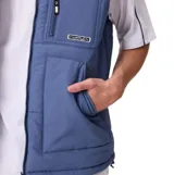 Chaleco acolchado reversible de la marca Rusty, color azul, con cierre frontal completo, cuello alto y bolsillos laterales. Presenta un bolsillo adicional con cierre en el pecho y etiqueta de la marca.