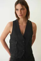 Chaleco de denim con proceso de encuerado, color negro, con escote en V, cierre frontal con botones y bolsillos delanteros con solapa.
