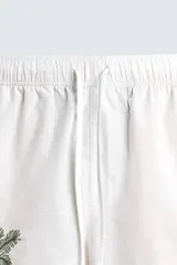 Bermuda de corte relajado confeccionada en algodón, color blanco con vivo en contraste color marrón en el ruedo. Presenta cintura elástica con cordón ajustable y un bordado decorativo en la pierna derecha que incluye una palmera y un gallo.