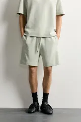 Bermuda estilo jogger de ajuste relajado, confeccionada en tejido interlock de algodón. Cuenta con cintura elástica ajustable con cordón, bolsillos frontales de vivo y diseño liso.
