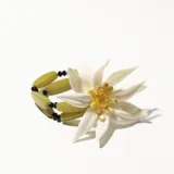 Pulsera elástica con cuentas de vidrio color verde oliva y negro, con dije de flor blanca con centro amarillo y naranja.