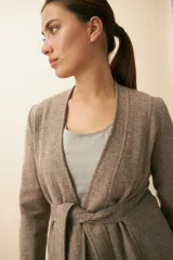 Chaqueta corta color beige, entallada, con escote en V, manga larga y bolsillos escondidos. Cierre frontal con lazo fijo. Confeccionada en lana fina sin teñir. Diseño exclusivo de Don Baez.