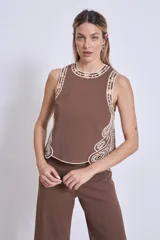 Blusa negra sin mangas, de corte recto y escote redondo, con detalles de bordados contrastantes en color blanco en los bordes y costados.