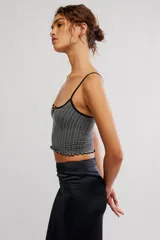 Top corto sin costuras de tejido acanalado y texturado color marfil, con escote redondo amplio, botonadura henley al frente con pequeños botones a presión, tiras finas fijas y terminación con ruedo en lechuga, de calce ajustado.
