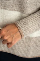 Sweater de punto con diseño de rayas horizontales anchas en color bordó y beige. Presenta cuello redondo con detalle de lurex, mangas largas y puños y ruedo acanalados.