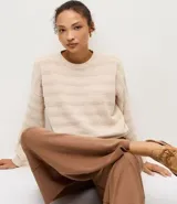 Blusa de punto ligero color beige, con diseño de rayas horizontales texturizadas, cuello redondo, mangas largas y terminaciones acanaladas en puños y ruedo.