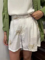 Shorts de tiro alto color marrón con estampado de pequeños rombos blancos y un borde ancho con diseño de encaje o bordado estilo paisley en blanco.