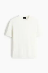 Remera de punto fino color blanco, con cuello redondo acanalado y mangas cortas, de corte slim fit.