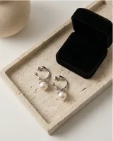 Aros colgantes de diseño orgánico en metal plateado con una perla central de acabado nacarado.