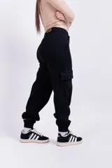 Pantalón mom cargo de jean negro con bolsillos laterales y tobillos ajustados.