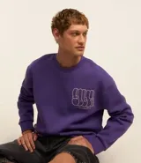 Buzo relaxed de algodón y poliéster color violeta con cuello redondo, puños y bajo acanalados. Estampa frontal con texto en color blanco.