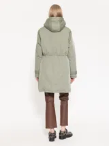 Parka verde militar de corte recto y holgado con cintura ajustable mediante cordón. Cuenta con capucha, bolsillos frontales con solapa y broches.