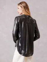 Camisa de manga larga con acabado satinado y efecto metalizado en color gris oscuro. Presenta cuello camisero clásico, cierre frontal con botones forrados y puños estructurados.