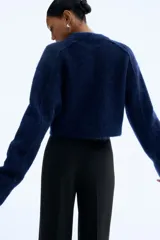 Pantalón sastrero negro de tiro alto con piernas amplias y pliegues marcados en el frente y la espalda.