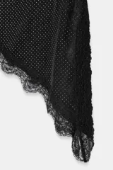 Top negro con estampado de lunares blancos, escote recto, tirantes finos, detalle de encaje en el escote y bajo asimétrico con abertura lateral.