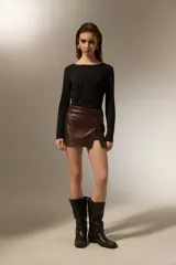 Minifalda de cuero sintético color negro, con diseño de tajo frontal y detalle de cinturón integrado con tachas metálicas en la cintura.