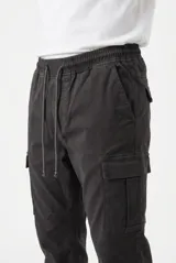 Pantalón jogger cargo color beige, con bolsillos laterales en las piernas, cintura elástica con cordón ajustable y puños en los tobillos.