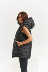 Chaleco negro oversize con capucha forrada en tela gamuzada, cierre metálico YKK, bolsillos laterales y tancas regulables en el ruedo.