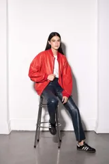 Campera bomber de cuero vacuno en color rojo, con corte oversized y diseño retro. Presenta cuello, puños y pretina de tejido de punto acanalado en tono a juego, cierre frontal y bolsillos laterales. El interior está completamente forrado en algodón.