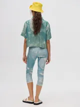 Camisa corta celeste con estampado de nubes, cuello clásico, manga corta y cierre frontal con botones.