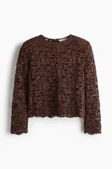 Blusa de manga larga en encaje marrón oscuro con patrón floral. Presenta escote redondo y un borde festoneado en el bajo.